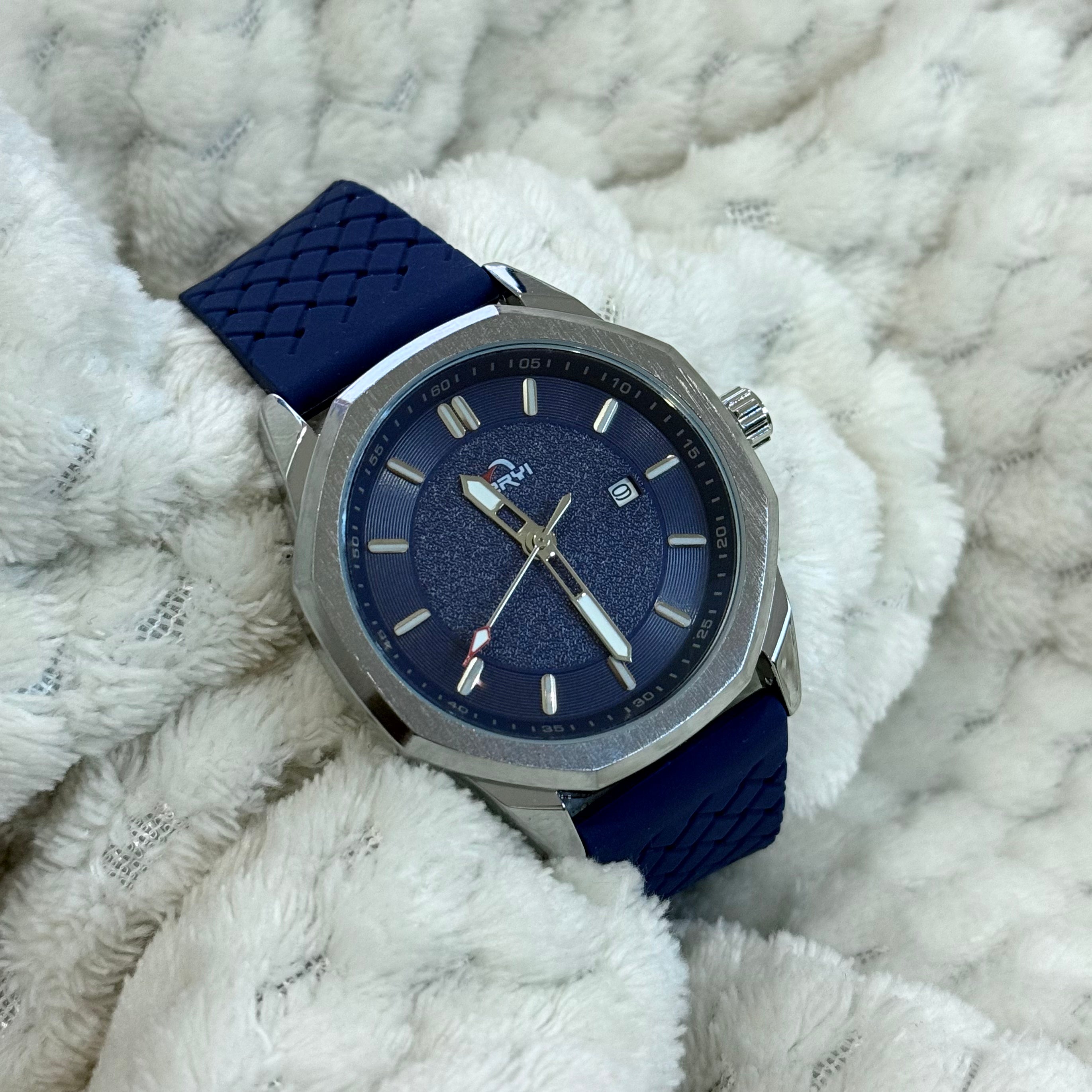 Wristwatch with blue strap and navy dial on a textured white surface